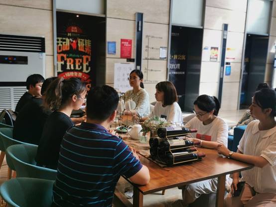 一群人坐在桌子前描述已自动生成 一群人坐在桌子前描述已自动生成